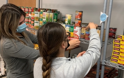 Two students stock a food shelf