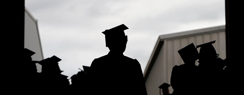 A silhouette of graduates in caps and gowns