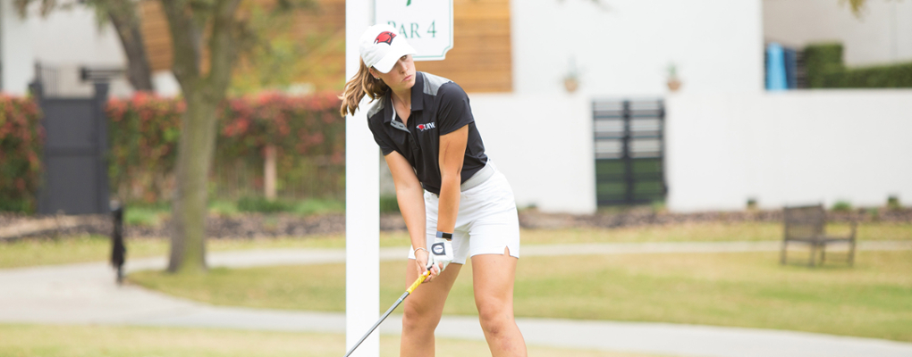 A golf player lines up her swing