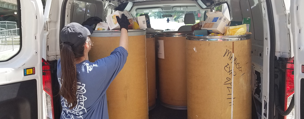 A woman loads the back of a vehicle with food donations