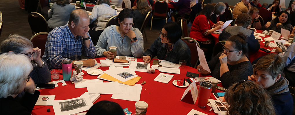 Faculty members sit at a table and discuss the content of their professional development