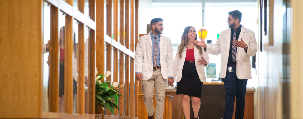 Three pharmacy students walk down a hallway