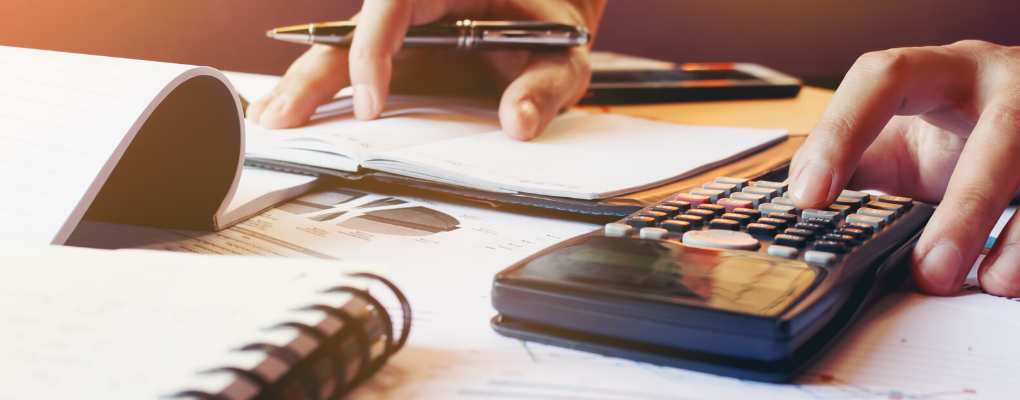 A person uses a calculator and notebook at a desk