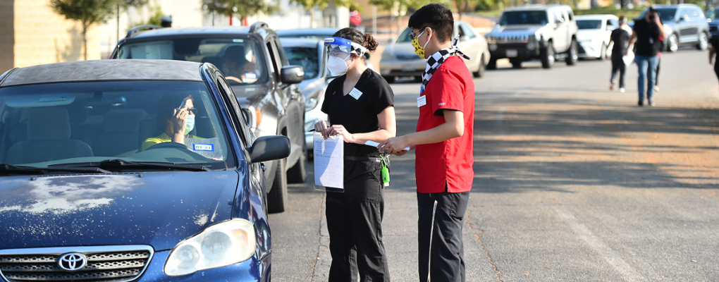 UIW students approach a vehicle to administer a vaccine