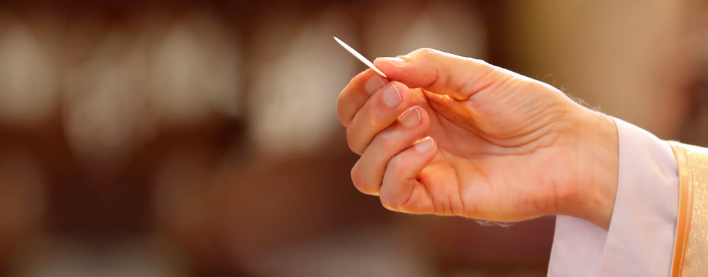 A priest holds his hand out with communion 