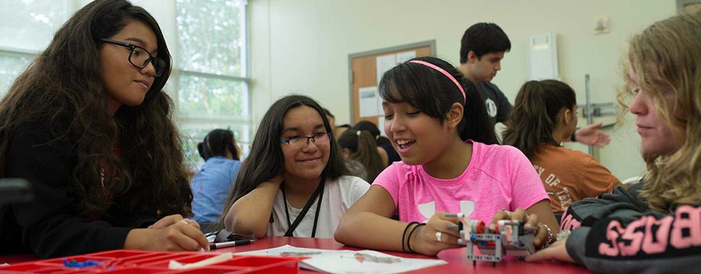 A group of students gather around a desk