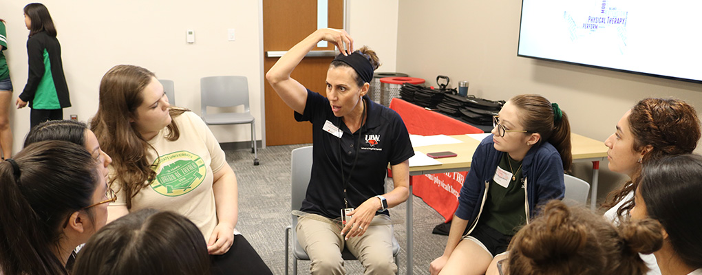 UIW staff member sits in a circle with high school students explaining information about the human body