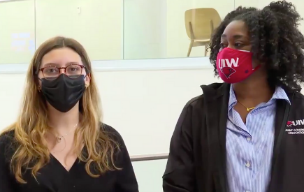 Two students in masks stand side by side in a screen grab of a news story