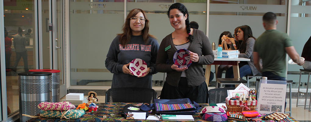 Two women hold up items for sale at International Bazaar 