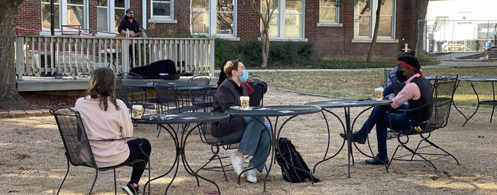 Students converse at tables outdoors