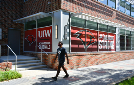 A student wearing a mask walks through the UIW campus