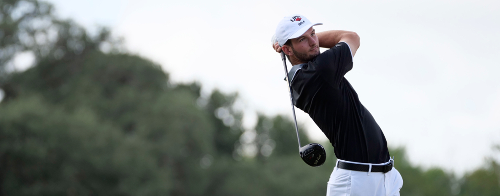 A golfer looks out on the course after his swing