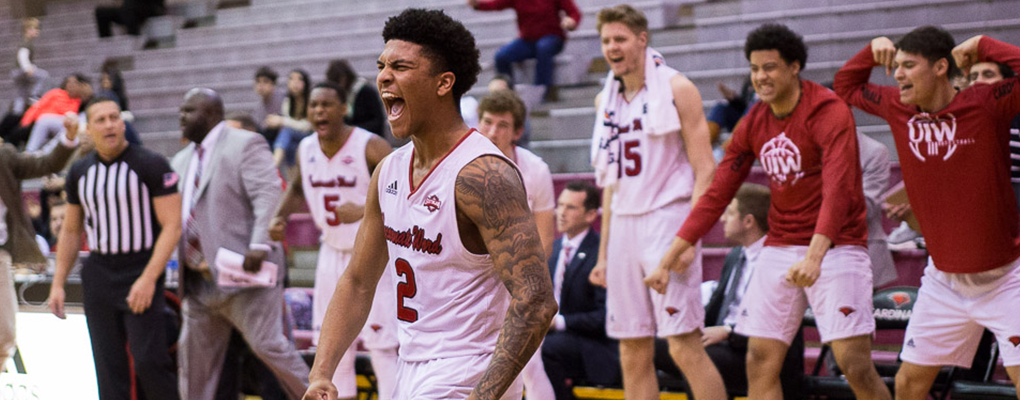 A basketball player yells in celebration on the sideline 