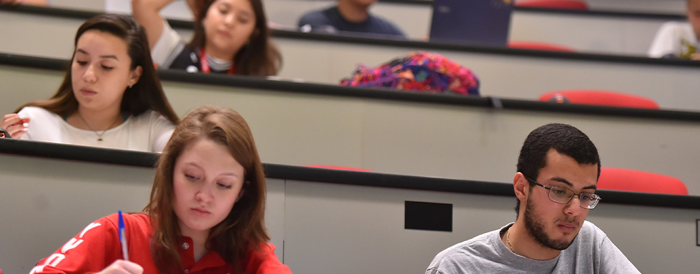 Students sit at desks in a lecture hall