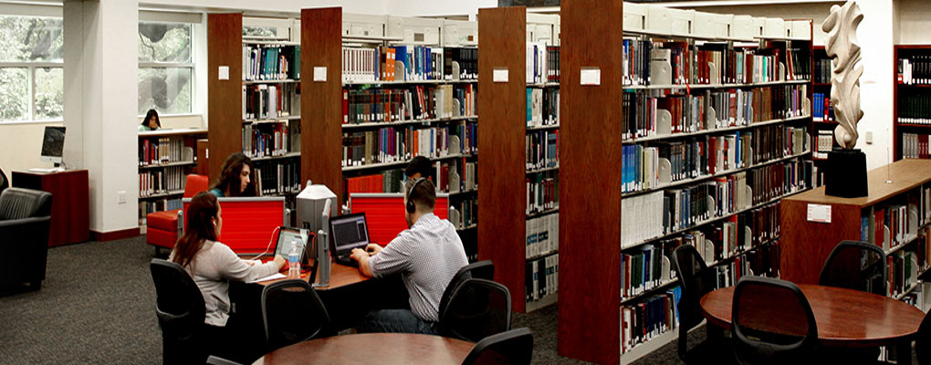 A group of students sit at a table in a library