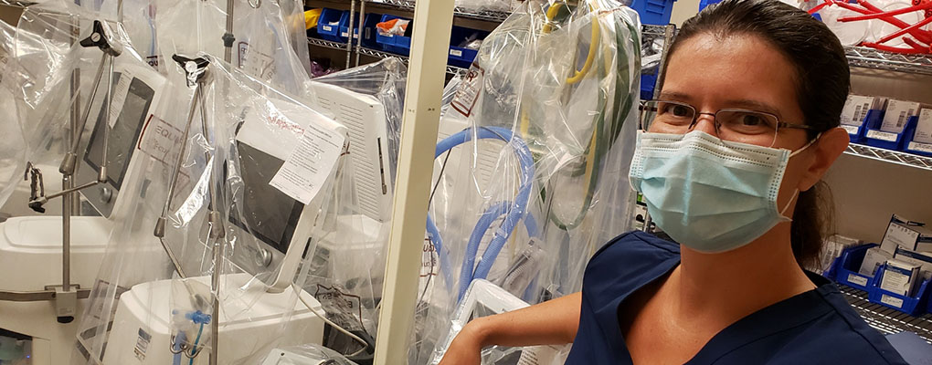 A nurse wearing a mask stands in front of nursing equipment