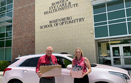 Two people pose for a photo holding boxes of hand sanitizer