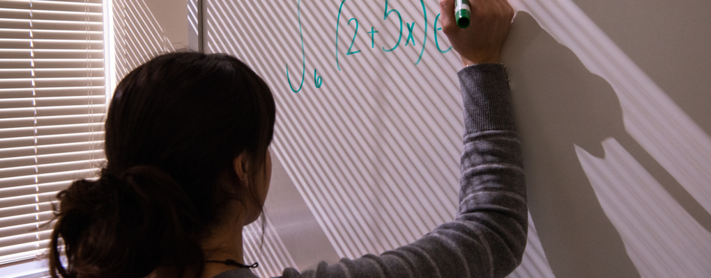A student works on an equation on a white board