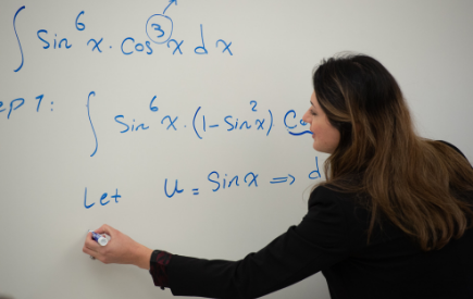 A woman solves an equation on a white board