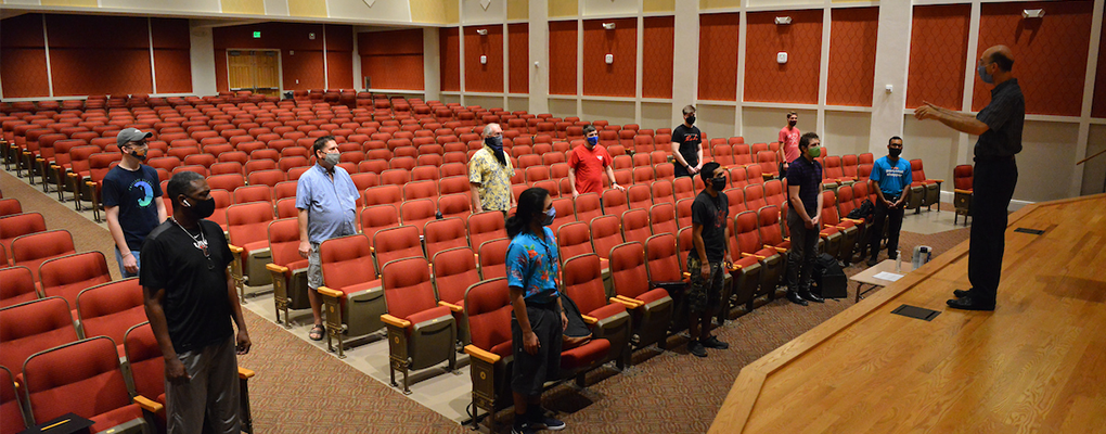 A choir stands far apart in a performance hall