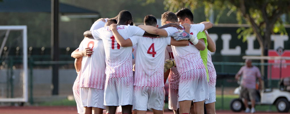The men's soccer team gather in a huddle