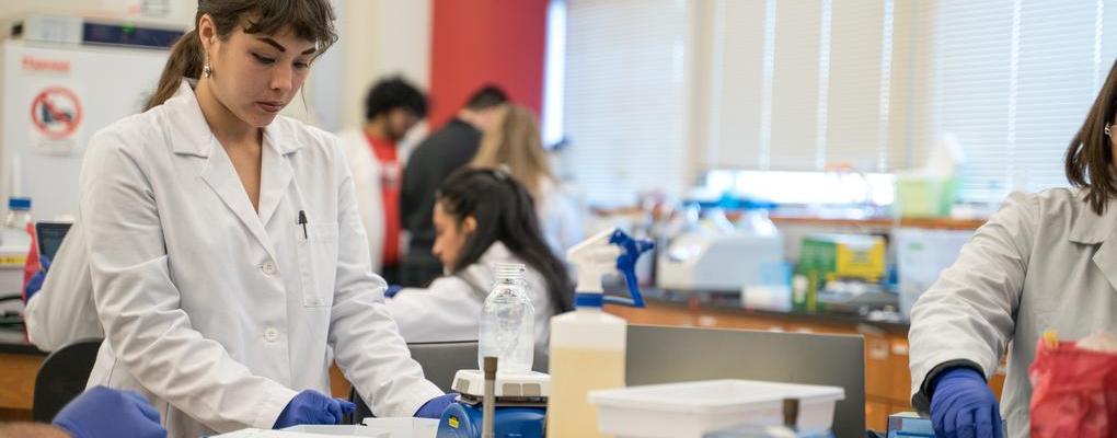 A student in a white coat in a science lab
