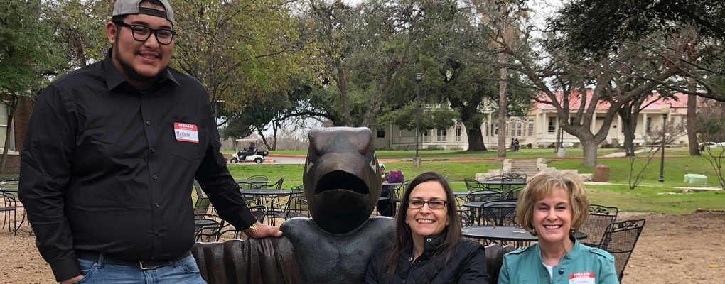 3 people pose for a photo together on a bench