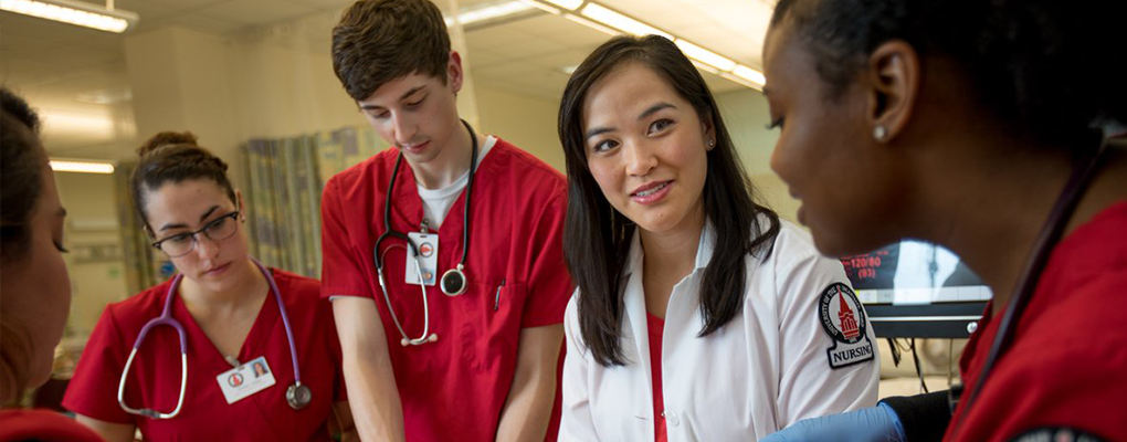 A group of nursing students and a professor gather in a huddle