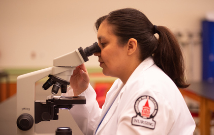 A nursing student uses a microscope
