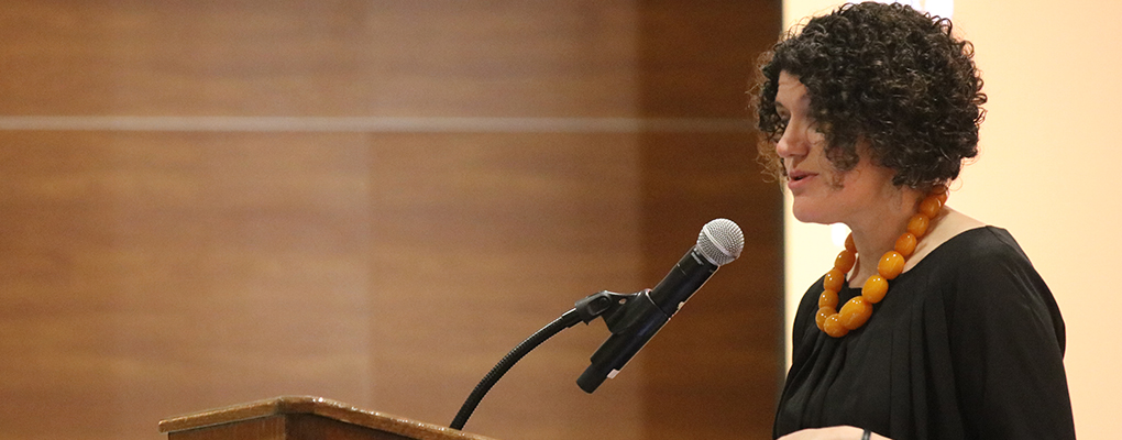 A woman speaks into a microphone at a podium