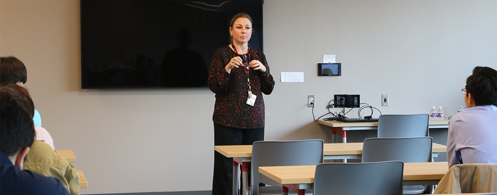 A woman speaks in front of a class