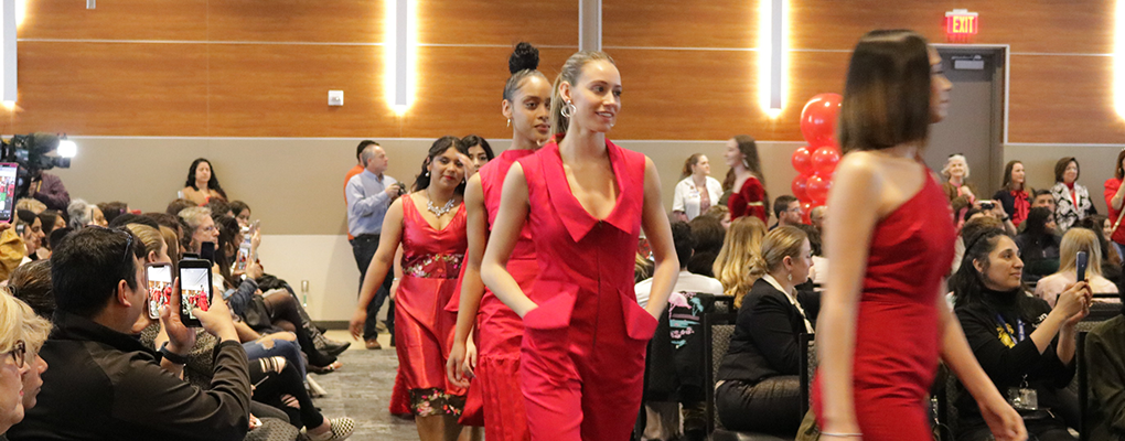 Models in red garments walk down the runway