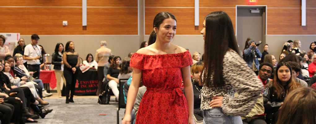 A model in a red dress poses on the runway