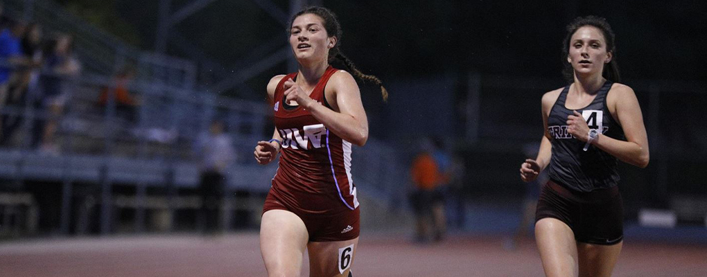 A UIW track team member runs down the track with a competitor close behind