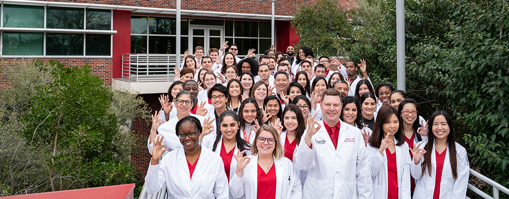 Pharmacy students in white coats pose for a group photo
