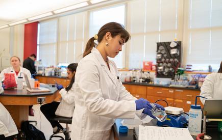 A student in a white coat in a science lab