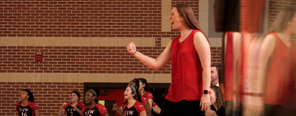 A volleyball coach cheers from the sideline
