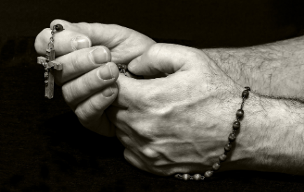 Hands folded in prayer holding a rosary