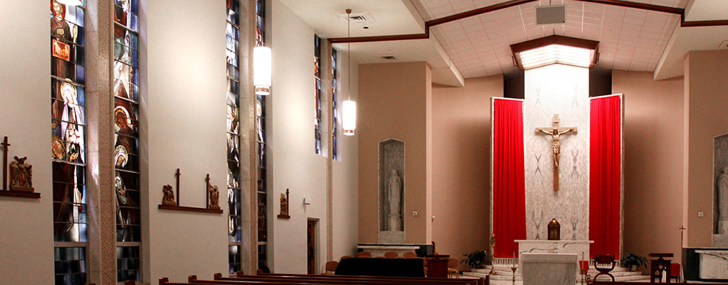 A chapel with a cross, red drapes and an altar 