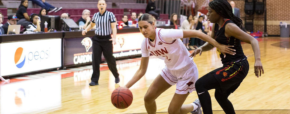 A UIW women's basketball player dribbles the ball as a member of the opposing team tries to block her