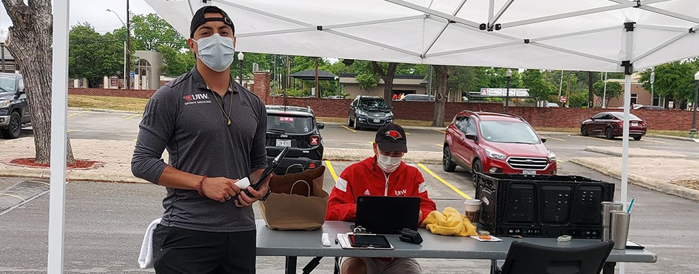 Two people in masks work at a tent