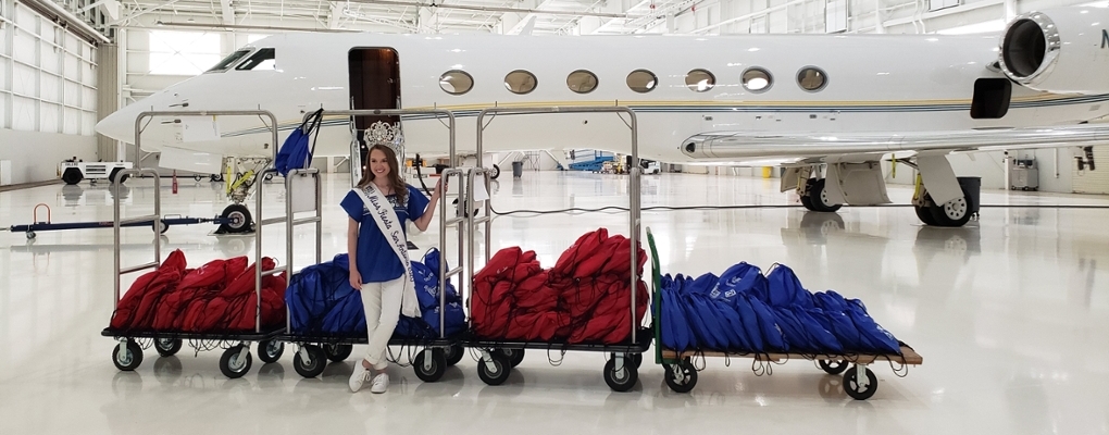 Calista Burns poses with STEAM kits in front of an airplane