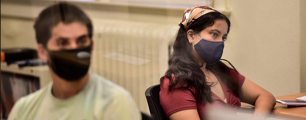 Students in masks sit in a classroom