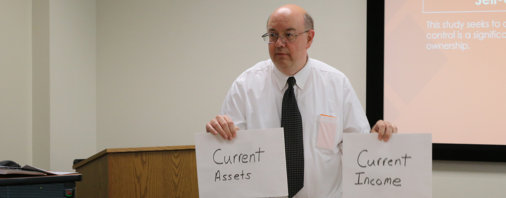 An instructor holds up signs with finance terms