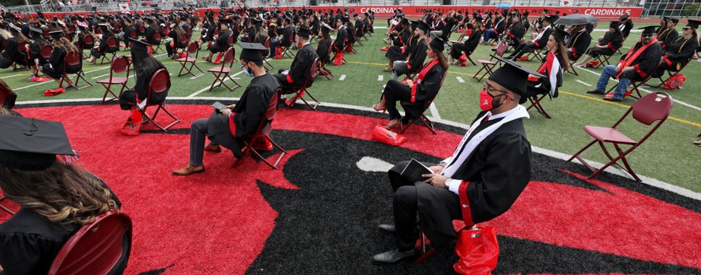 Graduates sit on the football field