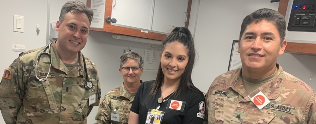 A nursing student smiles next to U.S. Army medical professionals