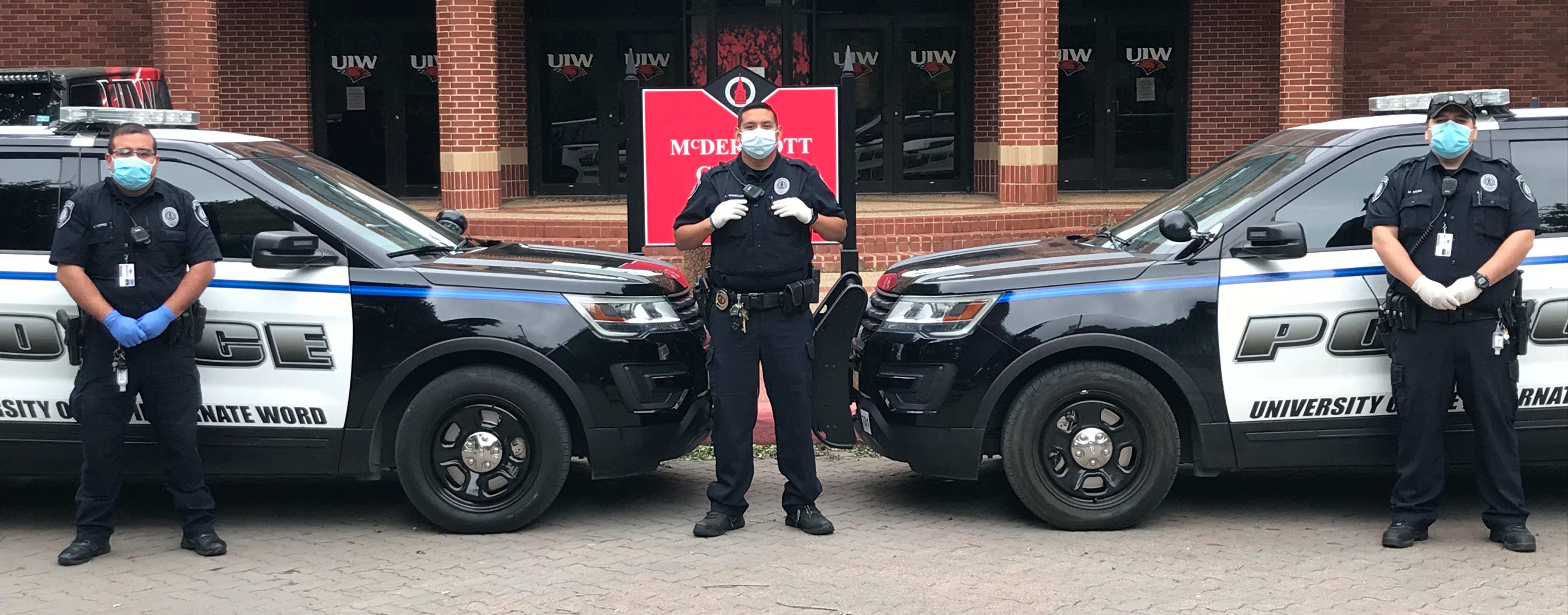 UIW police officers pose for a photo (while social distancing) wearing face masks in front of their vehicles