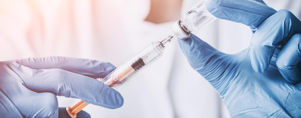 Gloved hands prepare a vaccine