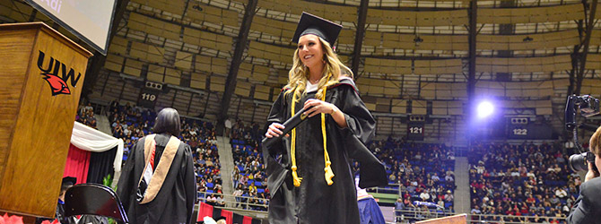 Graduation photo of student walking on stage to get her diploma